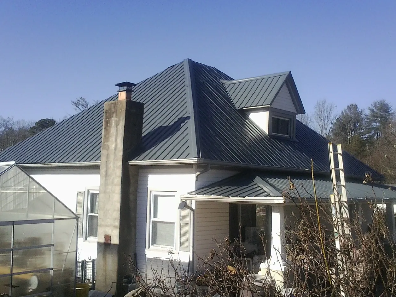 Dark blue standing seam metal roof on a white farmhouse with dormer — Slate & Tile Roof Repair by Roofing Brothers in Lake Station