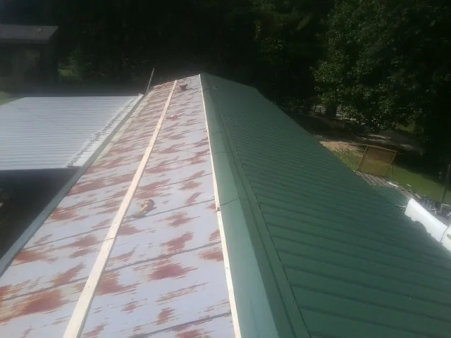 Old rusted panels beside newly installed green metal roofing — Wind Damage Roof Repair by Roofing Brothers in Lake Station