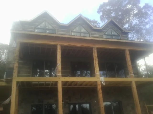 Dormers and porch framing on a large log home under construction — Roof Coating work by our crew in Lake Station
