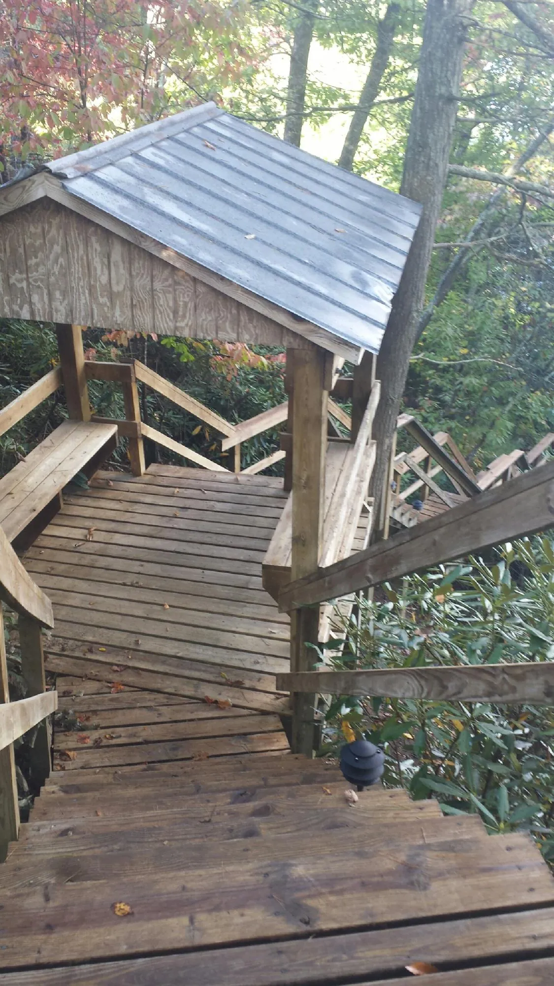 Metal roofed shelter over wooden steps on a wooded walkway — Skylight Repair & Installation work by our crew in Lake Station