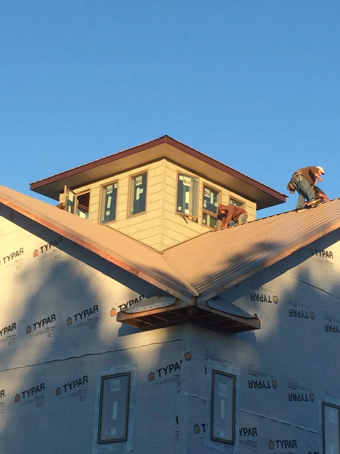 Roofers working around a rooftop cupola on a new metal roof at sunset — Roof Waterproofing in Lake Station by Roofing Brothers